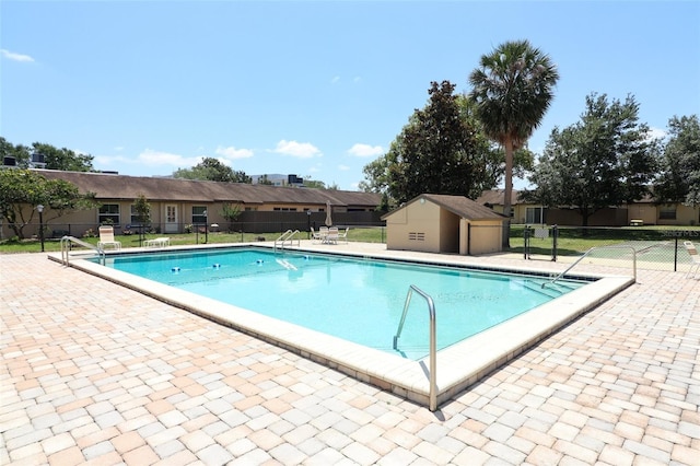 view of pool with a patio and a storage unit