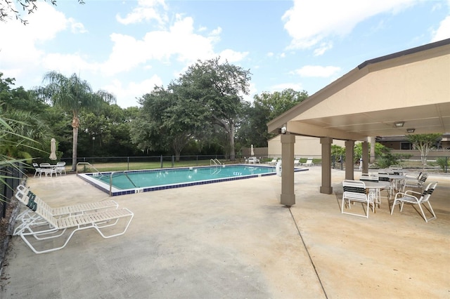 community pool featuring a patio, fence, and view of scattered trees