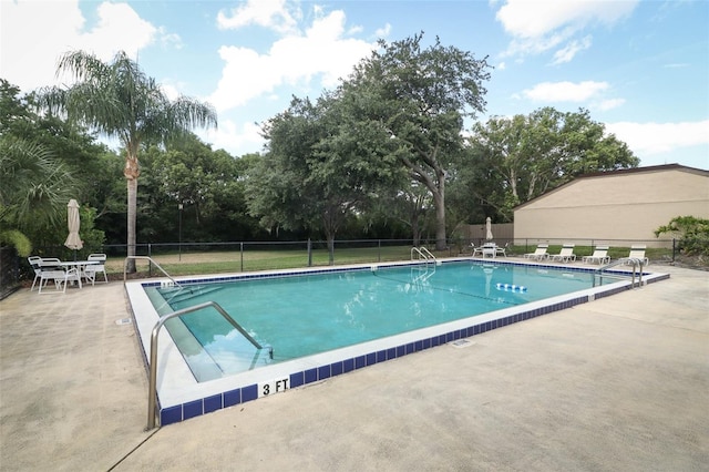 community pool featuring fence, a patio area, and view of scattered trees
