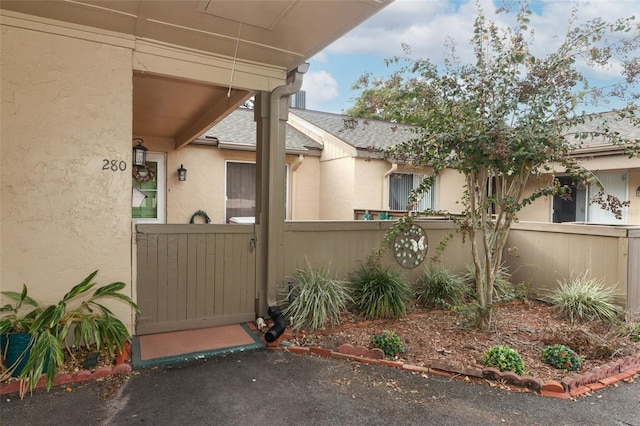 view of side of property featuring stucco siding, fence, and a gate