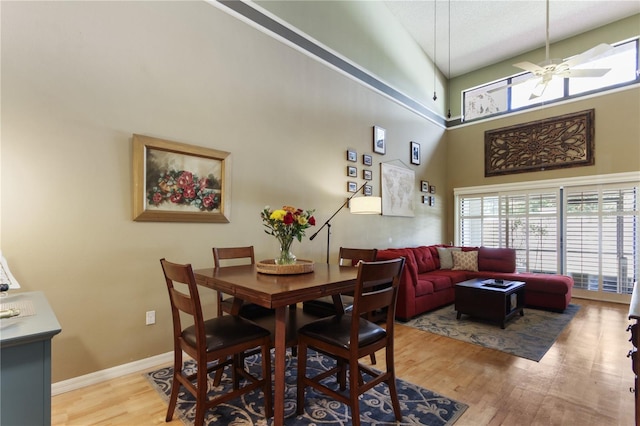 dining space featuring a towering ceiling, light wood-type flooring, and ceiling fan