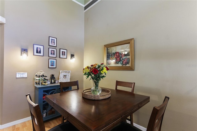 dining space with a high ceiling and light hardwood / wood-style floors