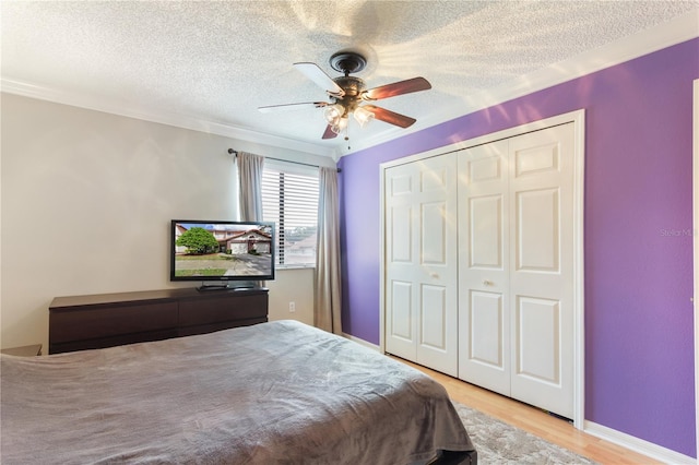 bedroom with a closet, crown molding, light wood-type flooring, a textured ceiling, and ceiling fan