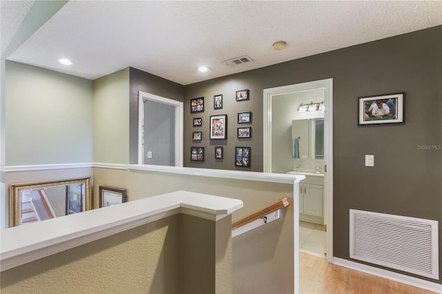 corridor featuring light hardwood / wood-style floors and a textured ceiling