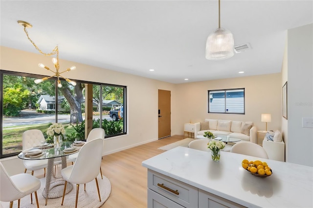 kitchen featuring a chandelier, pendant lighting, light stone counters, and light wood-type flooring