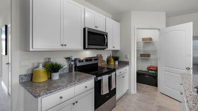 kitchen with white cabinetry, stainless steel appliances, stone counters, and light tile patterned floors