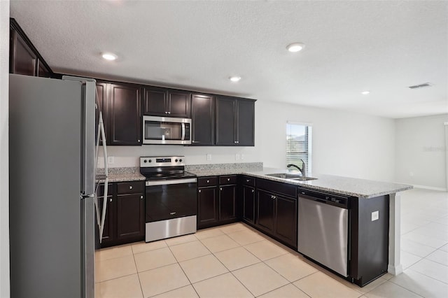 kitchen featuring kitchen peninsula, light stone countertops, sink, and appliances with stainless steel finishes