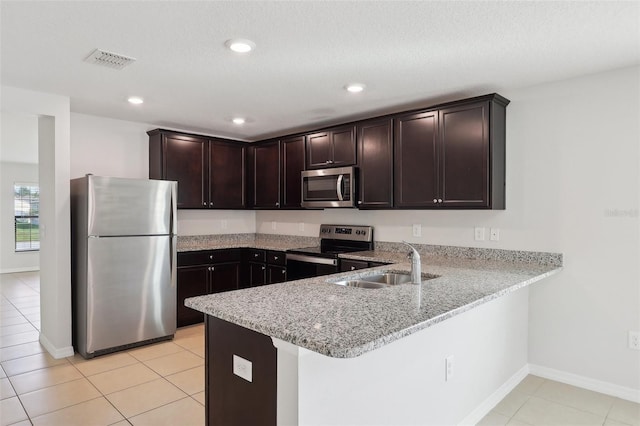 kitchen with sink, dark brown cabinetry, light tile patterned floors, appliances with stainless steel finishes, and kitchen peninsula