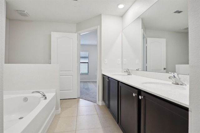 bathroom with tile patterned floors, a washtub, and vanity