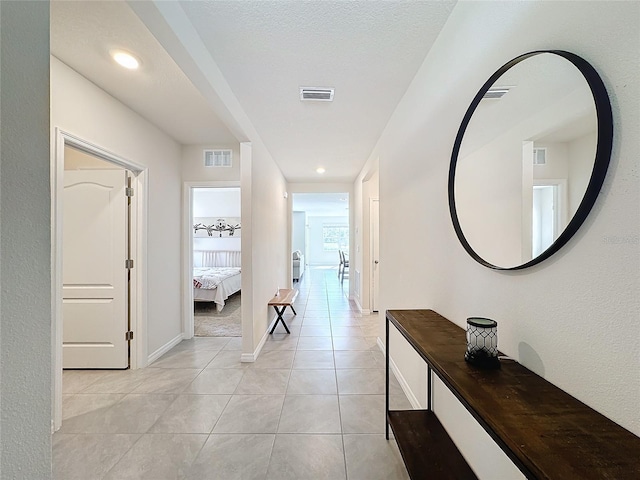 corridor featuring a textured ceiling and light tile patterned floors