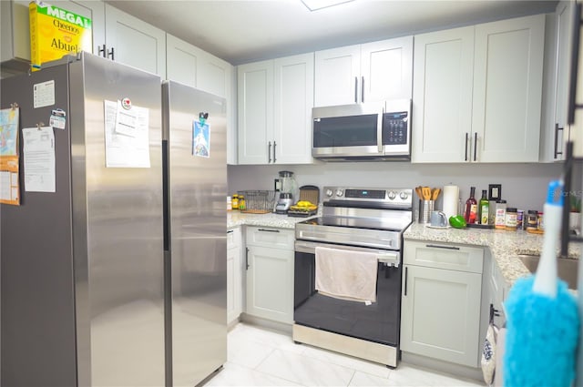 kitchen featuring white cabinets, light stone counters, and appliances with stainless steel finishes