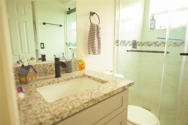 bathroom with a shower with door, vanity, and toilet