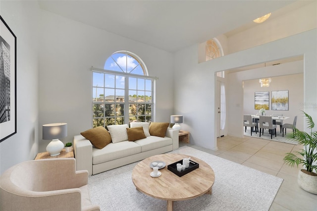 living room with a high ceiling, a chandelier, and light tile patterned floors