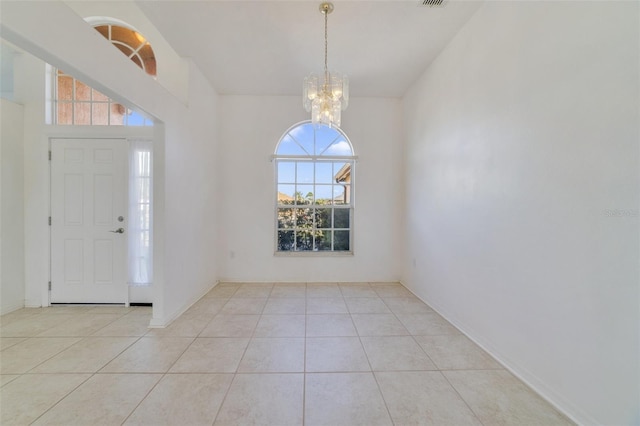 foyer entrance with light tile patterned floors and an inviting chandelier