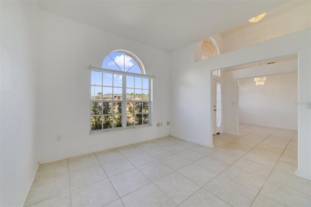 unfurnished room with a chandelier and light tile patterned floors