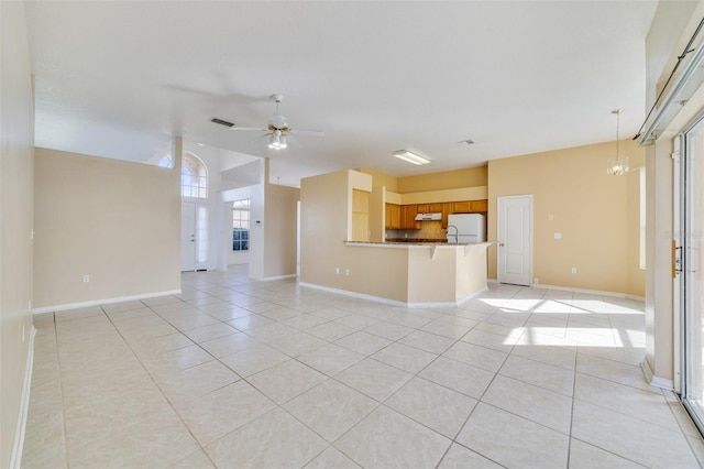 unfurnished living room featuring light tile patterned flooring and ceiling fan with notable chandelier