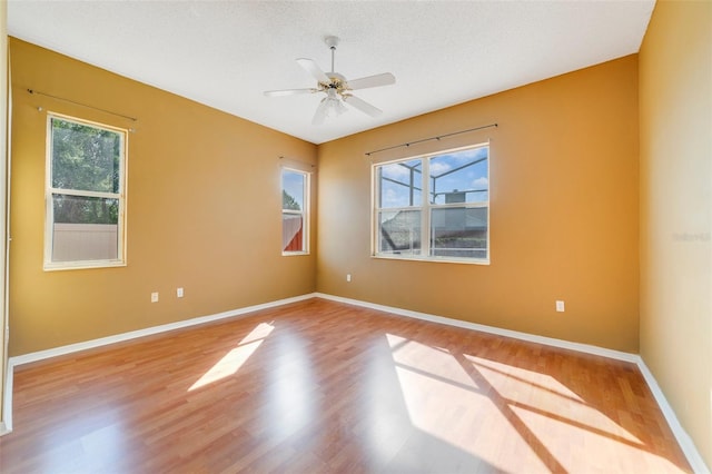 spare room with a wealth of natural light, hardwood / wood-style flooring, and ceiling fan