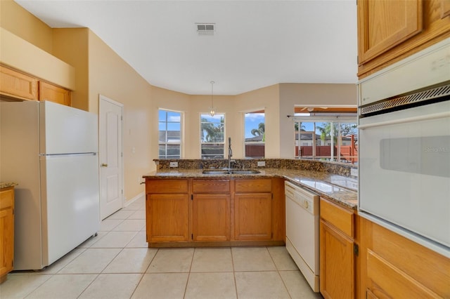 kitchen with kitchen peninsula, light tile patterned floors, pendant lighting, sink, and white appliances