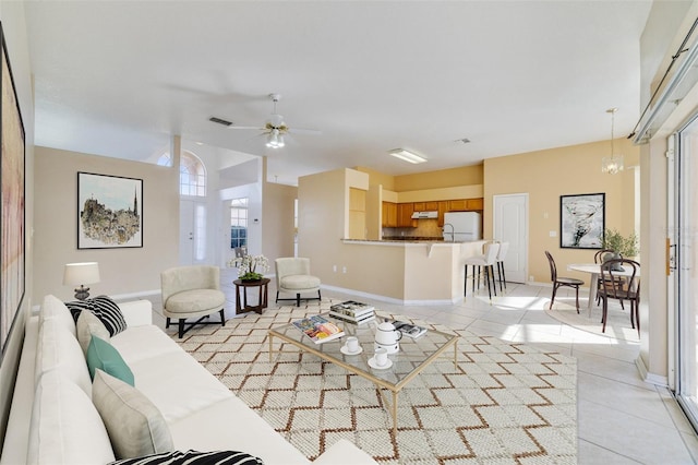 tiled living room featuring ceiling fan with notable chandelier