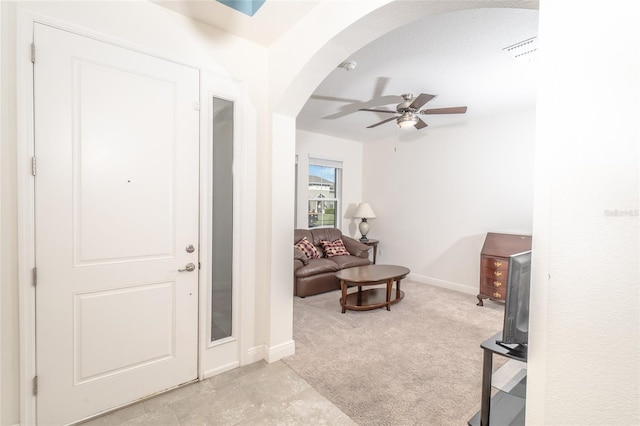 foyer featuring ceiling fan, light carpet, and a textured ceiling