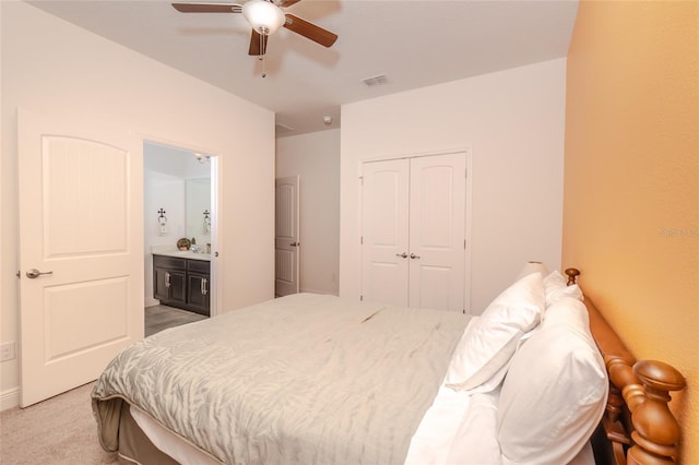 carpeted bedroom with a closet, ceiling fan, and ensuite bathroom