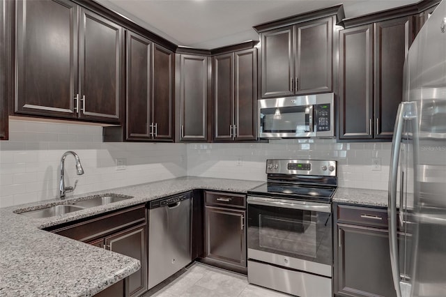 kitchen with dark brown cabinets, stainless steel appliances, light stone countertops, and sink