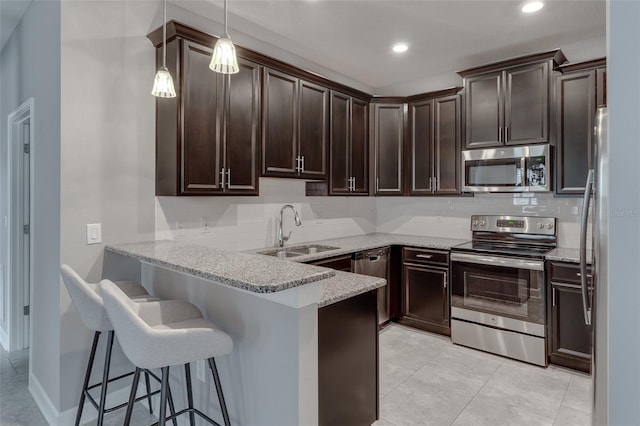 kitchen featuring hanging light fixtures, sink, a breakfast bar, appliances with stainless steel finishes, and tasteful backsplash