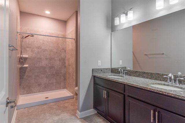 bathroom featuring vanity, a tile shower, toilet, and tile patterned flooring