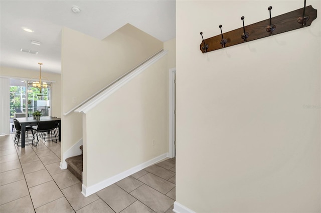 staircase with an inviting chandelier and tile patterned flooring