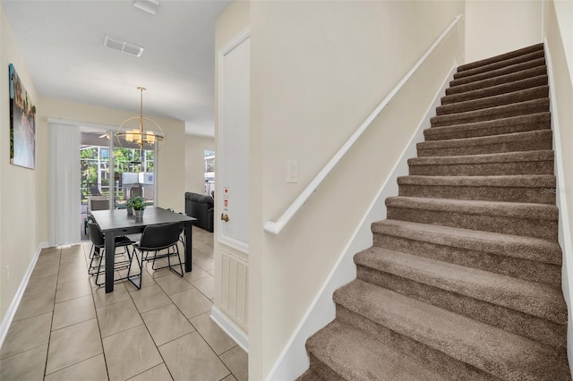 stairway with tile patterned floors and a notable chandelier