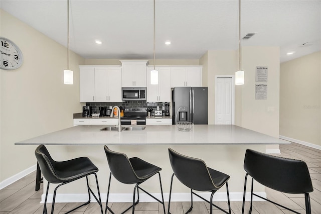 kitchen featuring a spacious island, backsplash, sink, white cabinetry, and appliances with stainless steel finishes