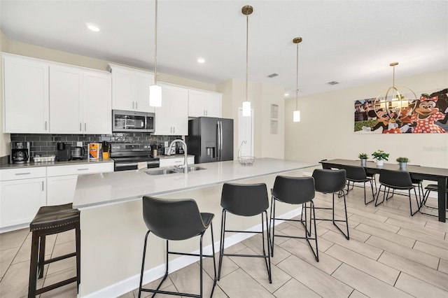 kitchen with white cabinets, stainless steel appliances, hanging light fixtures, and a kitchen bar