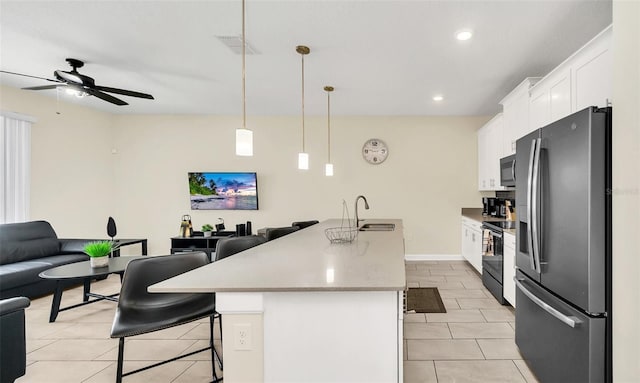 kitchen with appliances with stainless steel finishes, hanging light fixtures, white cabinets, a breakfast bar, and a center island with sink