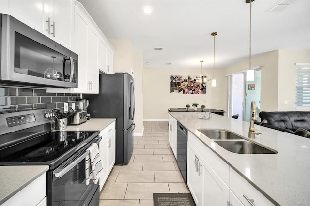 kitchen featuring appliances with stainless steel finishes, sink, white cabinetry, decorative light fixtures, and an inviting chandelier