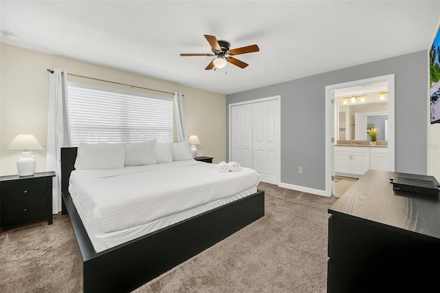 carpeted bedroom with ensuite bath, a closet, and ceiling fan