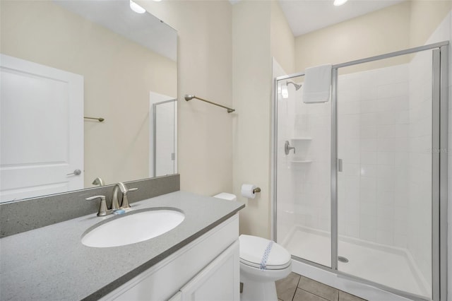 bathroom with vanity, a shower with shower door, toilet, and tile patterned floors