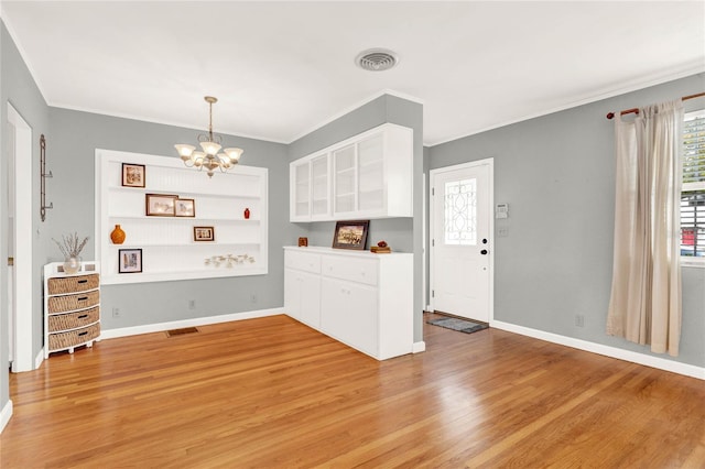 kitchen with white cabinetry, crown molding, wood-type flooring, and an inviting chandelier