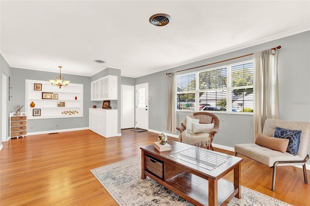 living room featuring wood-type flooring, an inviting chandelier, and crown molding