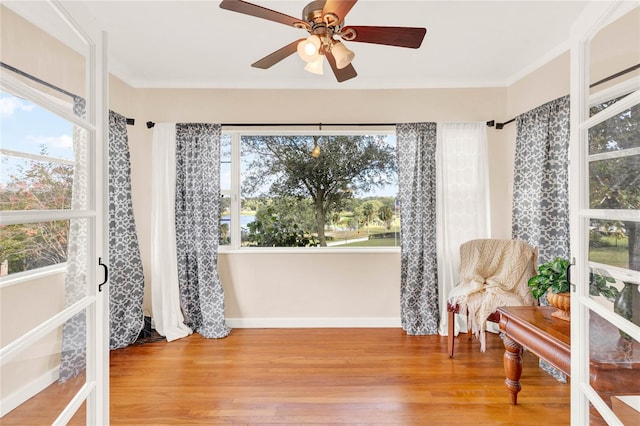 sitting room with ceiling fan, ornamental molding, and light wood-type flooring