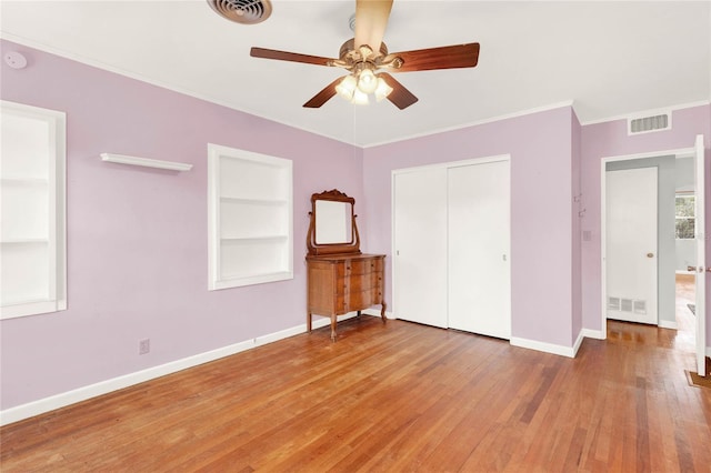 unfurnished bedroom featuring hardwood / wood-style flooring, ceiling fan, crown molding, and a closet