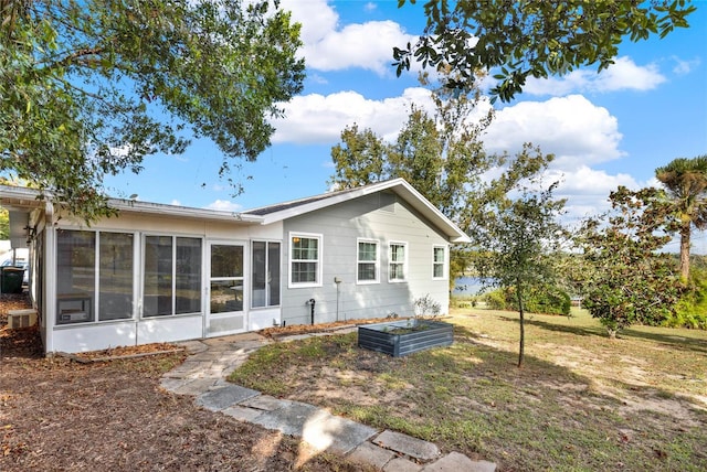 back of house featuring a sunroom and a lawn