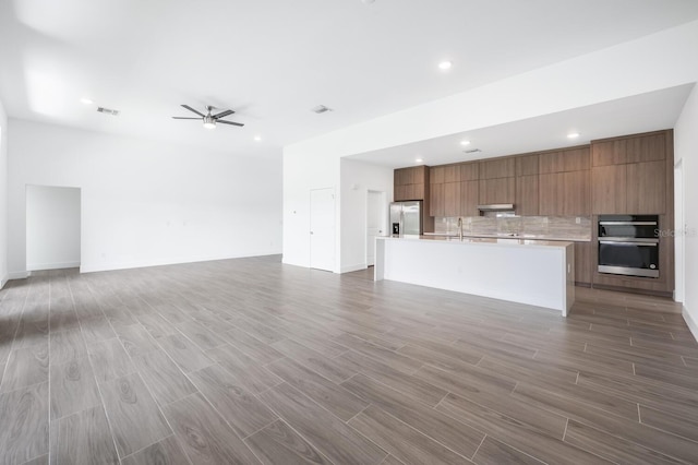 unfurnished living room featuring ceiling fan and sink