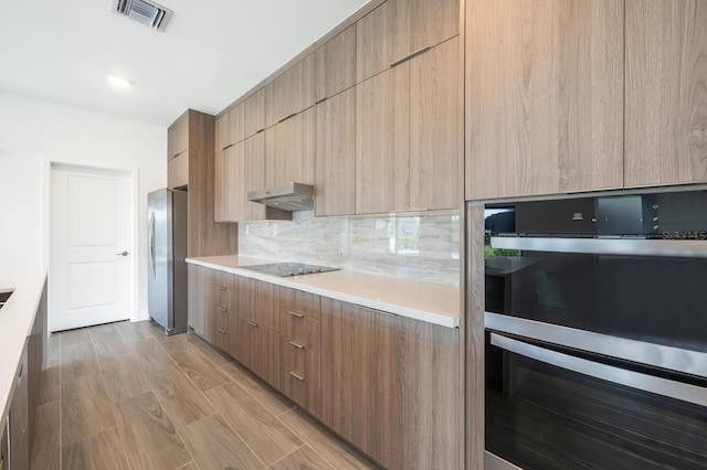 kitchen featuring stainless steel appliances, tasteful backsplash, and light brown cabinetry