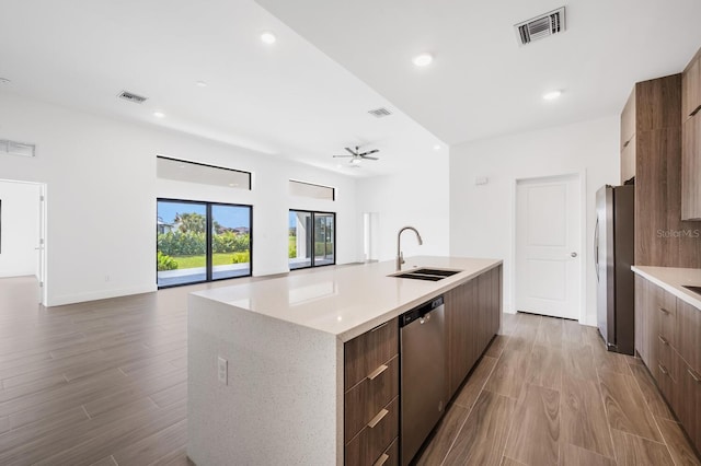 kitchen featuring sink, a large island with sink, ceiling fan, stainless steel appliances, and light hardwood / wood-style flooring