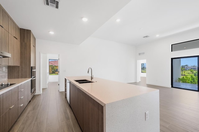 kitchen featuring sink, a wealth of natural light, black electric cooktop, and a spacious island