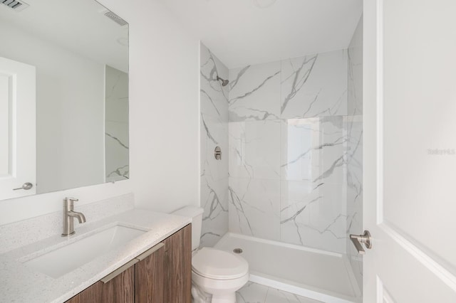 bathroom featuring vanity, toilet, and tiled shower