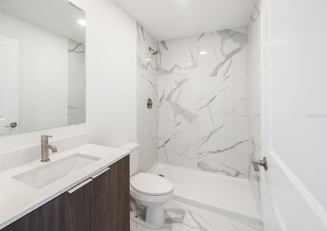 bathroom with vanity, toilet, and a tile shower