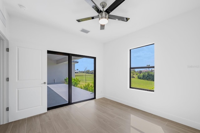 empty room with ceiling fan, plenty of natural light, and light hardwood / wood-style flooring