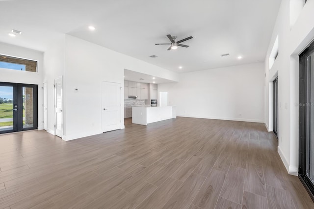 unfurnished living room featuring french doors, ceiling fan, and light wood-type flooring