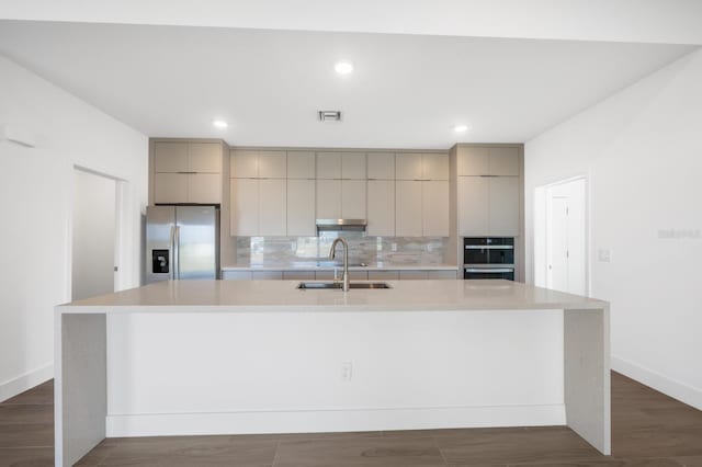 kitchen featuring decorative backsplash, sink, stainless steel fridge, and a spacious island